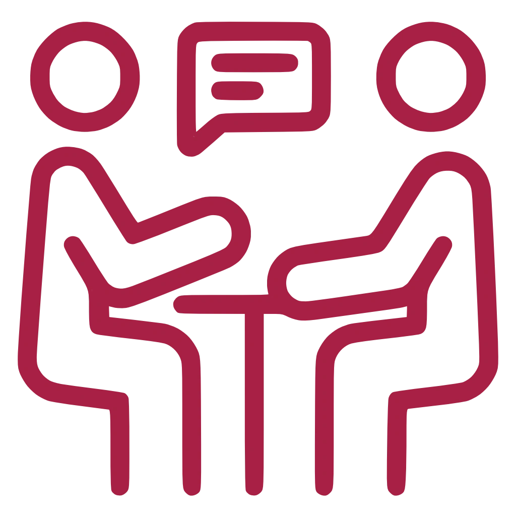 Das Icon zeigt zwei Personen, die sich an einem Tisch gegenübersitzen. Über der linken Person ist eine Sprechblase.